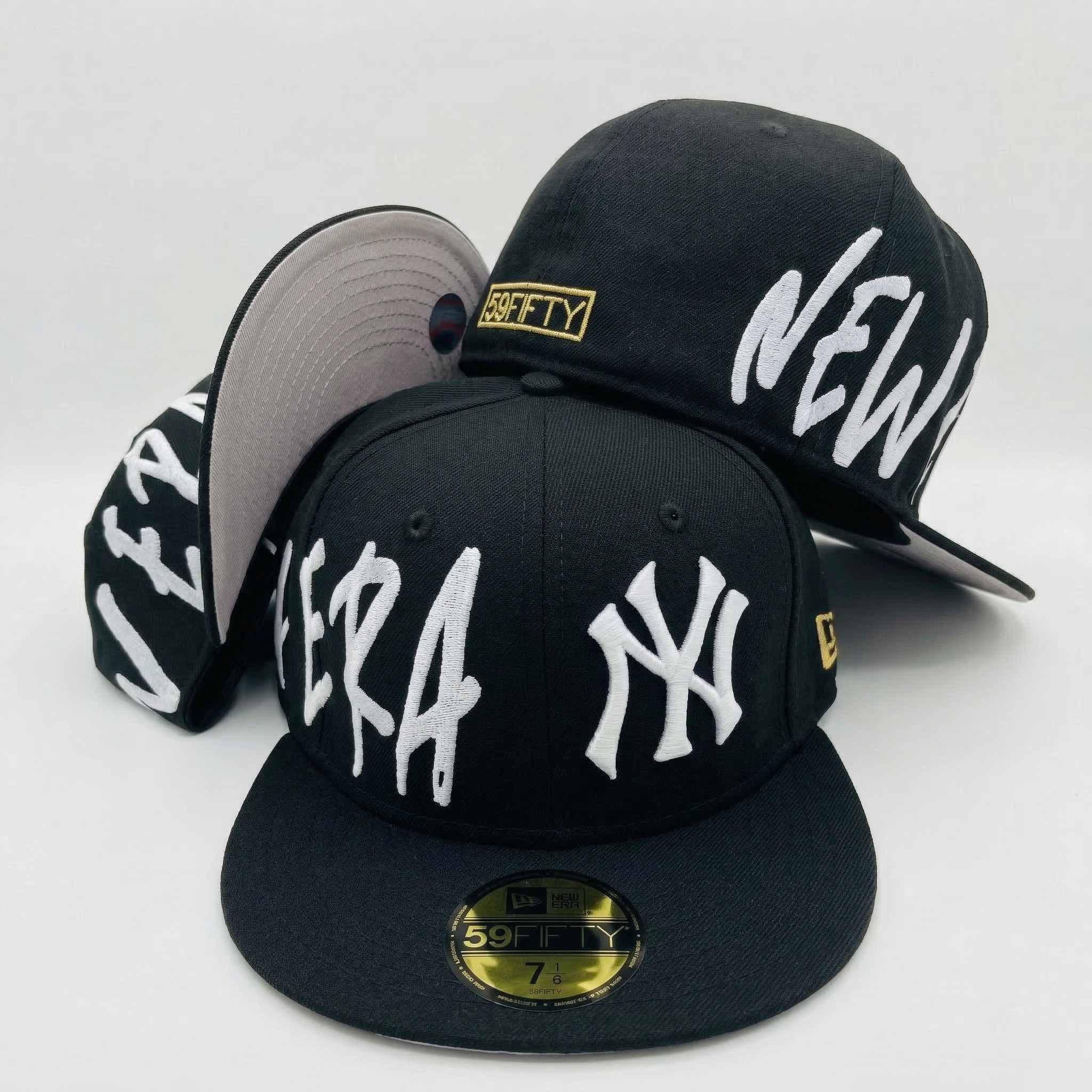 Group of black New York Yankees fitted hats displaying multiple angles of the wrap-around white 'NEW ERA' script design and a grey undervisor.