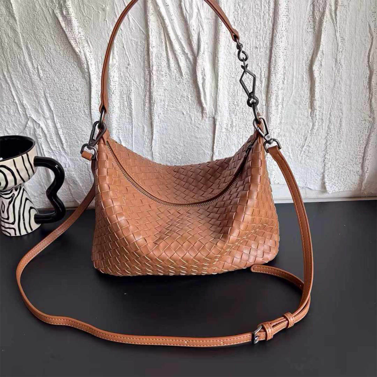 A versatile bag designed to be carried by hand, on the shoulder, or crossbody. Crafted from double-sided woven cowhide, it features an interior zippered compartment for convenient organization.