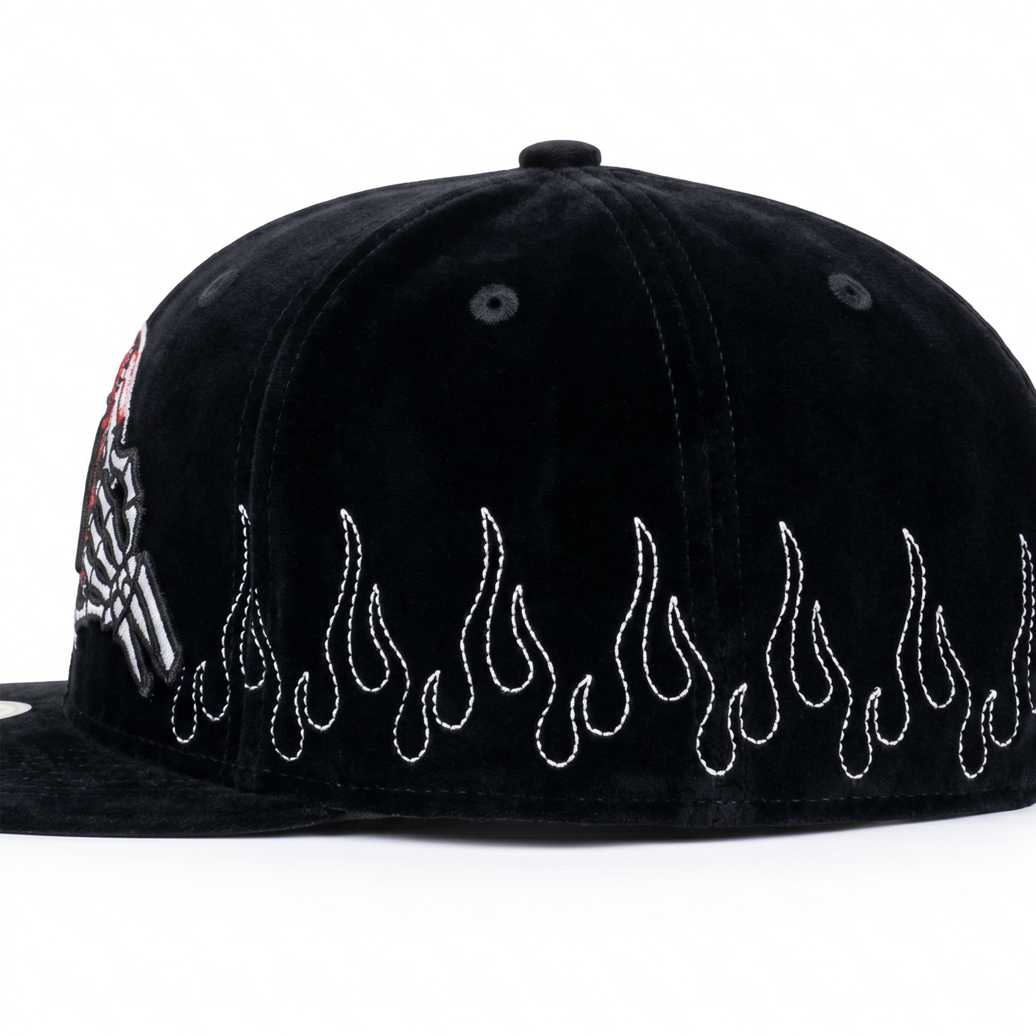 Angled view of a custom black velvet baseball hat highlighting white flame embroidery and a skeleton hand logo on the front.