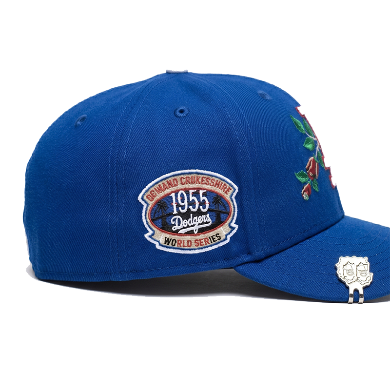 Close-up view of the right side of the Los Angeles Dodgers fitted hat, highlighting the detailed 1955 World Series commemorative patch and the custom silver metal accessory clipped to the brim.